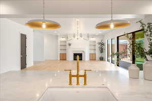 Kitchen with open floor plan, light stone countertops, a fireplace, and built in shelves