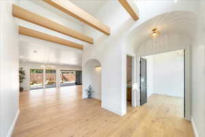 Hall featuring suspended lighting, light wood-style flooring, and arched walkways
