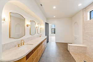 Bathroom with healthy amount of natural light, double vanity, recessed lighting, and dark tile patterned floors