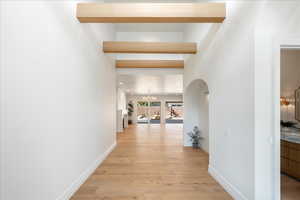 Corridor featuring light wood-style flooring, hanging lights, and arched walkways