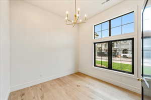 Empty room featuring light wood finished floors and a chandelier