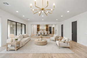 Living room with recessed lighting, light wood-type flooring, and a chandelier