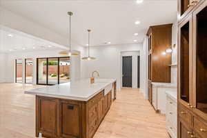 Kitchen featuring brown cabinetry, recessed lighting, hanging light fixtures, a large island, and light wood finished floors