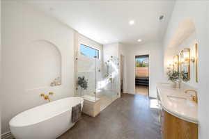 Bathroom featuring healthy amount of natural light, a soaking tub, double vanity, a stall shower, and recessed lighting