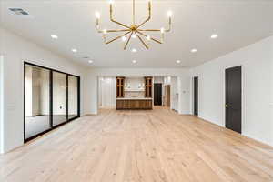 Unfurnished living room with light wood-type flooring, recessed lighting, and a chandelier