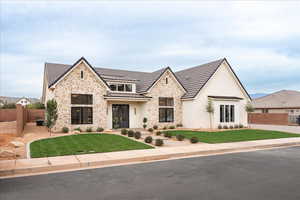 View of front of property with a standing seam roof, stone siding, a metal roof, and stucco siding