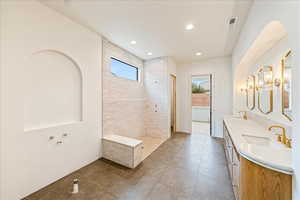 Bathroom featuring double vanity, walk in shower, dark tile patterned flooring, and recessed lighting