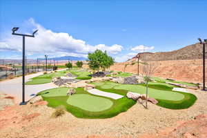 View of property's community with a putting green, a mountain view, and a patio