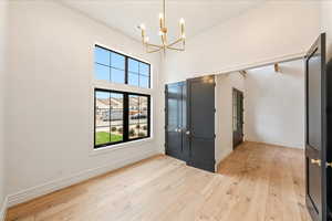 Entrance foyer featuring light wood-type flooring, a chandelier, and a high ceiling