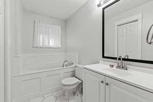 Bathroom featuring a textured ceiling, a bath, tile patterned flooring, and vanity