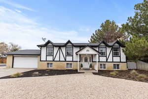View of front of property featuring brick siding, concrete driveway, a garage, and stucco siding