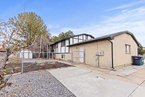 Back of property with a gate, brick siding, and a storage unit