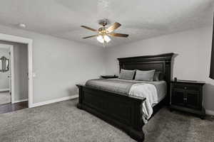Bedroom featuring dark carpet, a textured ceiling, and ceiling fan