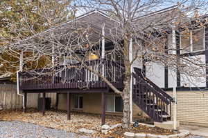 Back of property featuring stairs and a wooden deck