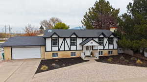 View of front of house with brick siding, concrete driveway, and a chimney