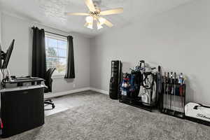 Carpeted home office featuring a textured ceiling and a ceiling fan