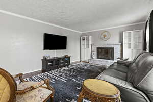 Living area featuring ornamental molding, wood finished floors, a fireplace, and a textured ceiling