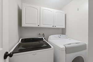 Washroom featuring independent washer and dryer and cabinet space