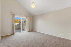 Spare room featuring light colored carpet and high vaulted ceiling