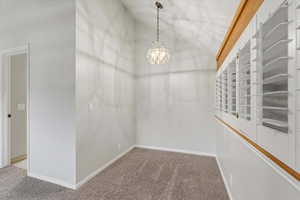 Carpeted empty room with a chandelier and vaulted ceiling