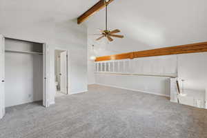 Unfurnished bedroom featuring high vaulted ceiling, beamed ceiling, carpet, ensuite bathroom, and a ceiling fan