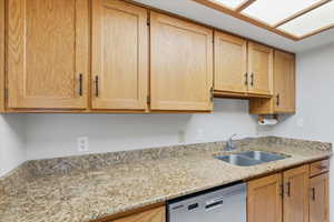 Kitchen featuring light stone countertops, dishwasher, and light brown cabinets