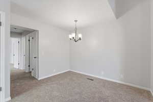 Family/dining room with light colored carpet and a chandelier