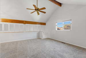 Empty room with high vaulted ceiling, beamed ceiling, light colored carpet, and ceiling fan