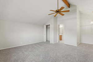 Unfurnished bedroom featuring high vaulted ceiling, beamed ceiling, light colored carpet, a closet, and a ceiling fan