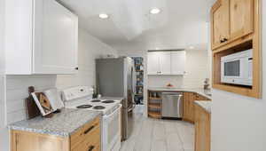 Kitchen with appliances with stainless steel finishes, light stone countertops, recessed lighting, white cabinetry, and open shelves