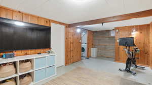 Exercise area with wooden walls, light flooring, beamed ceiling, and washer / clothes dryer