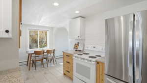 Kitchen with freestanding refrigerator, white electric range, recessed lighting, light stone counters, and light wood-style floors