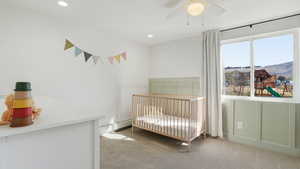 Bedroom with light carpet, a crib, a mountain view, a ceiling fan, and recessed lighting