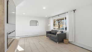 Living area with light wood-type flooring, recessed lighting, and baseboard heating