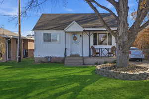 View of front of house with a front lawn and roof with shingles