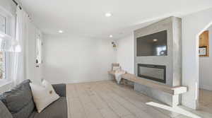 living room with a large fireplace, wood tiled floors, and recessed lighting
