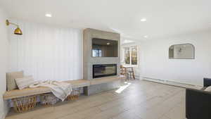 Living room featuring recessed lighting, a baseboard heating unit, wood finished floors, and a fireplace