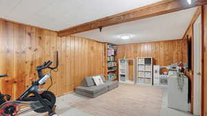 Workout room featuring wood walls, beamed ceiling, and tile patterned floors