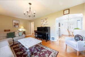 Living room with a chandelier, light wood-style flooring, and arched walkways