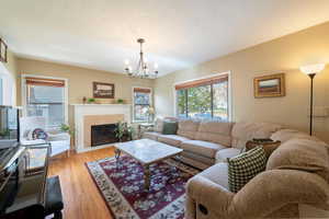 Living area featuring light wood-style floors, a high end fireplace, a chandelier, and a textured ceiling