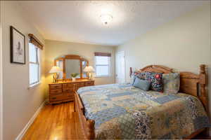 Bedroom with light wood-style floors and a textured ceiling