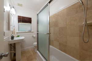 Full bathroom with ornamental molding, shower / bath combination with glass door, and tile patterned flooring