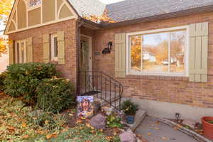 Doorway to property with brick siding and roof with shingles