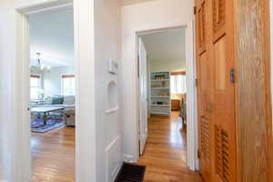 Hallway with light wood-style floors, a chandelier, and a textured ceiling