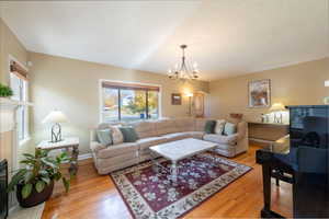 Living area with a glass covered fireplace, light wood-type flooring, a chandelier, and arched walkways