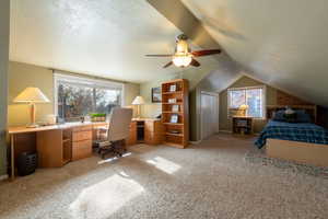 Bedroom with light colored carpet, a desk, a textured ceiling, ceiling fan, and vaulted ceiling