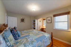 Bedroom featuring wood finished floors, a textured ceiling, and arched walkways