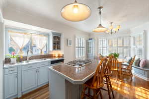 Kitchen featuring ornamental molding, a kitchen bar, a center island, dark wood-type flooring, and plenty of natural light