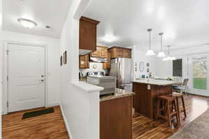 Kitchen featuring a breakfast bar area, dark wood-style flooring, a center island, and freestanding refrigerator
