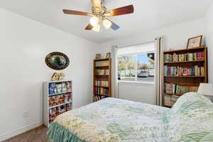 Carpeted bedroom with a ceiling fan and baseboards